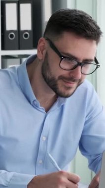 Beyaz erkek mali danışman ofiste belgelerle çalışıyor. Ticari evrakları ya da yıllık raporları düzenleyin. Dikey video.