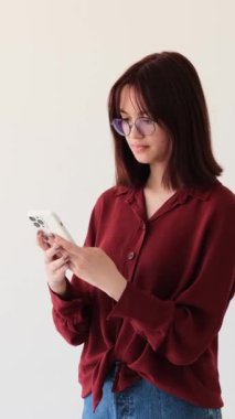 Mutsuz Kafkasyalı genç kız internette mesajlaşıyor ve beyaz arka plandaki başarısızlık ya da kayıptan dolayı üzülüyor. Dikey video.