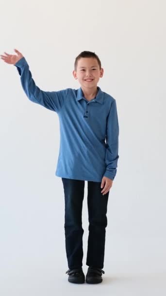 快乐的亚洲小男孩挥手致意 站在白色的背景上 欢迎男孩 敬礼的概念 垂直录像 — 图库视频影像