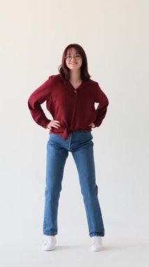 Neşeli beyaz kız dans ediyor ve boş zamanlarını beyaz arka planda geçiriyor. Eğlence ve dinlenme ile meşgul. Dikey video.