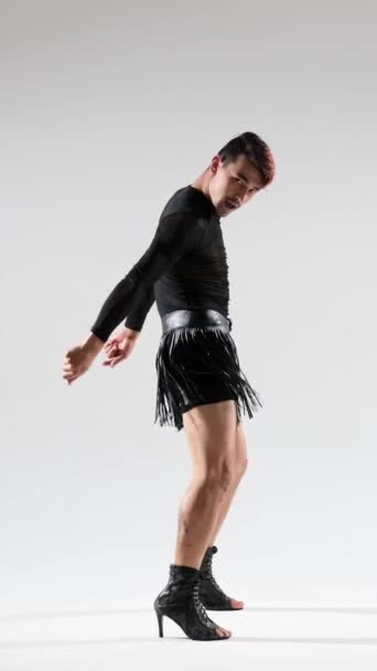 ハイヒールとスカートでエネルギッシュで柔軟なコーカサス人男性 白い背景の上に流行 現代の振付 バーティカルビデオ — ストック動画