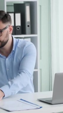 Ofiste evrak işleriyle uğraşan ciddi bir beyaz erkek ofis çalışanı. Planlama şirketi bütçesi, iş denetimi. Dikey video.
