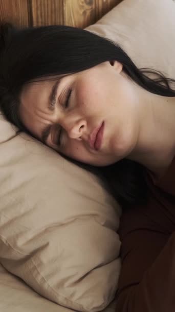 朝目覚めている白人女性は 携帯電話から そしてまだ寝て 自宅の寝室でベッドに横たわっている バーティカルビデオ — ストック動画