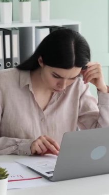 Konsantre Kafkas kadın serbest çalışan büroda evrak işleriyle meşgul. Mali veriler ve bilgiler analiz ediliyor. Dikey video.