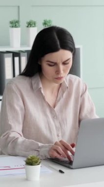Belgeler ve dizüstü bilgisayarla çalışan düşünceli beyaz kadın, ofiste işe başlamayı planlıyor ve kayıp ya da başarısızlıktan dolayı üzülüyor. Dikey video.