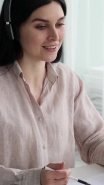 Ofiste çalışırken müşteriye danışan Kafkas kadın çağrı merkezi ajanı. Satış departmanını destekliyor. Dikey video.