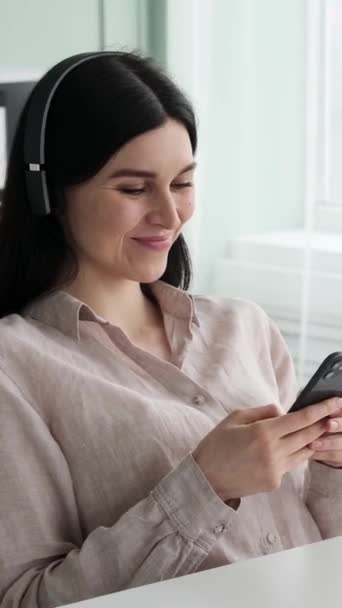 Uśmiechnięta Biała Bizneswoman Używająca Telefonu Słuchająca Muzyki Słuchawkach Biurze Relaks — Wideo stockowe