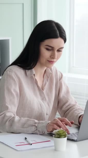 陽気な女性の白人オフィスワーカーは ラップトップで現代のオフィスで働いています コンピュータを使用してテキスト チャット メッセージング バーティカルビデオ — ストック動画
