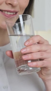 Kafkasyalı bir kadının portresi sabahları bardaktan temiz su içip eğleniyor. İyileşme ve su dengesi kavramı. Dikey video.
