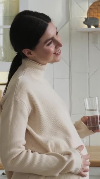 Mulher Grávida Branca Sorrindo Bebendo Água Acariciando Barriga Casa Cozinha — Vídeo de Stock