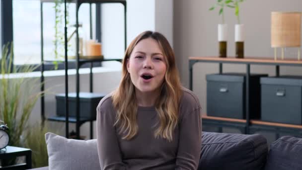 Förvånad Ung Vit Kvinna Utropar Wow Och Applåderar Sitter Soffan — Stockvideo