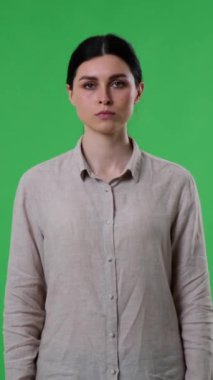 Ciddi bir beyaz kadının portresi, yeşil arka plan konusunda çelişen avuç içi ile dur işareti gösteriyor. İçki yasağı, koruma. Dikey video.