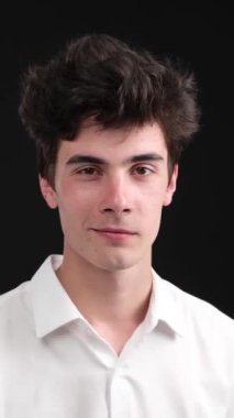 Siyah arka planda sessiz kalma hareketi yapan Kafkas asıllı bir genç. Parmağını dudağına sok. Dedikodu ve gizlilik kavramı. Dikey video.