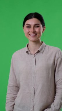 Tatmin olmuş ve iyimser beyaz kadın yeşil arka planda işaret gibi bir şey gösteriyor. Onaylama, anlaşma konsepti. Dikey video.