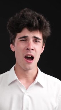 Siyah arka planda esneyen uykusuz ve yorgun Kafkas genci. İş yorgunluğu, yorgunluk konsepti. Uykusuzluk yüzünden. Dikey video.