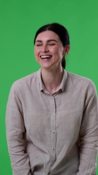 楽観的で喜ばしい白人女性は緑の背景を笑う ポジティブで満足した感情の概念 バーティカルビデオ — ストック動画