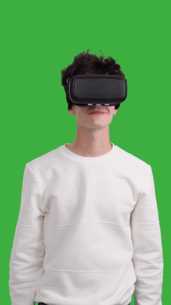 クロマキーバックグラウンドでVrヘッドセットを使用して幸せで楽しい白人青年 イノベーションテクノロジー 未来的なエンターテインメント バーティカルビデオ — ストック動画