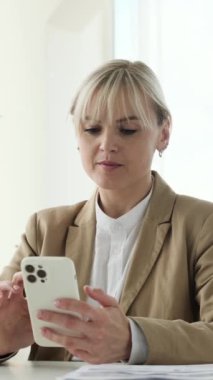 Neşeli Kafkasyalı iş kadını cep telefonuyla iyi haberler alıyor, Wow diye bağırıyor ve başarıyı kutluyor. Zafer ya da zafer kavramı. Dikey video.