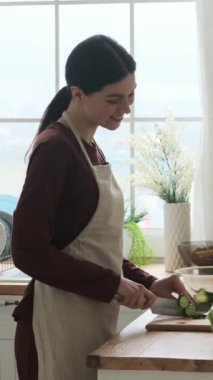 Mutlu beyaz kadın bıçakla sebze doğruyor, mutfakta lezzetli organik salata yapıyor. Taze ve sağlıklı yiyecekler. Dikey video.