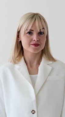 Dost canlısı beyaz kadın beyaz arka planda gizli bir sır ya da dedikodu sakladığı için şşşş hareketi yapıyor. Dikey video.