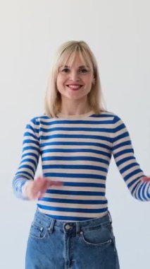 Beyaz arka planda kalp şeklinde el işareti gösteren neşeli beyaz kadın. Şefkat, romantizm, şefkat konsepti. Dikey video.