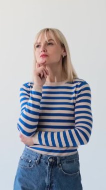 Düşünceli beyaz kadın beyin fırtınası yapıyor, parmağını havaya kaldırıyor, parlak bir fikri var ve beyaz arka planda mutlu oluyor. Dikey video.