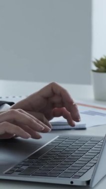 Ofisteki dizüstü bilgisayarın klavyesinde yazı yazan Hintli kadın elleri kapatın. Ofis çalışanı konsepti. Dikey video.