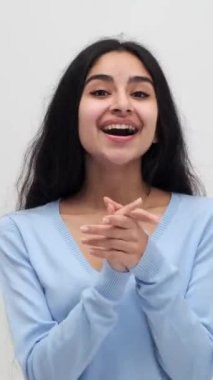 Heyecanlı genç Hintli kadın beyaz arka plan için tebrik ediyor ve takdir ediyor. Memnuniyet ve keyif. Dikey video.