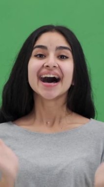 Tatmin olmuş Hintli kadın gülümseyip el çırpıyor. Yeşil arka plan için tebrik ediyor ve saygı gösteriyor. Memnuniyet ve kabullenme. Dikey video.