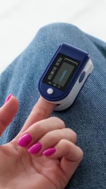 女人在家里分析心跳和检查氧饱和度 自监测电子设备脉冲血氧计 垂直录像 — 图库视频影像