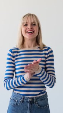 Tatmin olmuş ve neşeli beyaz kadın beyaz arka planda takdir edildiği için alkışlıyor. Anlaşma, destek, saygı konsepti. Dikey video.