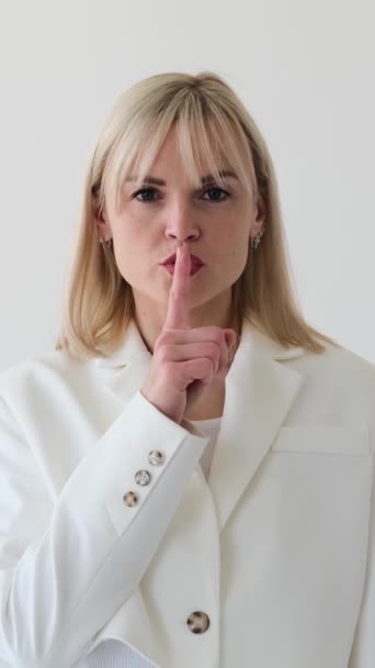 严重的白人女性员工表现出沉默的姿态 手指在嘴唇上 为隐私或保密的白色背景 垂直录像 — 图库视频影像
