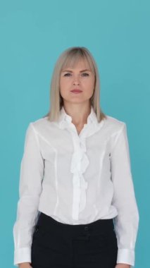 Hüsrana uğramış beyaz kadın ofis çalışanı mavi arka planda çapraz kollu dur işareti gösteriyor. Anlaşmazlık ve reddedilme. Dikey video.