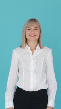 Dost canlısı, beyaz bir kadın tamam işareti gösteriyor, mavi arka planı onaylıyor. İyi seçim ya da karar konsepti. Dikey video.