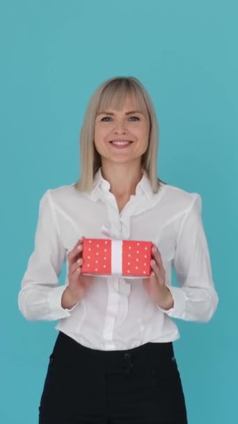 Neşeli Gülümseyen Beyaz Kadın Mavi Arka Planda Hediye Kutusunu Sunuyor — Stok video