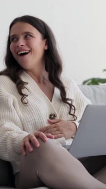 Evde dizüstü bilgisayarla konuşan beyaz bir kadın var. Çevrimiçi bağlantı ve internet sohbet konsepti. Dikey video.