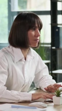 Ofiste bilgisayarla çalışırken orta yaşlı beyaz kadın ofis çalışanı başarısızlıktan depresyona girdi. Kötü haber ve zorluklar kavramı. Dikey video.