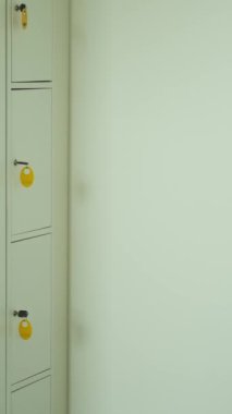 Kafkas kökenli orta yaşlı kadın vestiyerdeki bagaj ambarına kilitlenip ofis işi için hazırlanıyor. Dikey video.