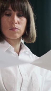 Kafkasyalı bir kadın çalışanın portresi. Belgelerle çalışıyor ve ofiste muhasebe işleriyle meşgul. Dikey video.