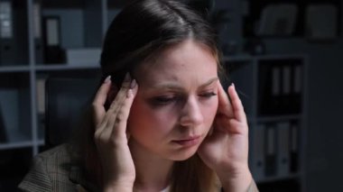 Geç saatlerde ofiste baş ağrısı ya da migreni olan mutsuz bir beyaz kadın ofis çalışanının portresi. Yorgun ve depresyon kavramı.