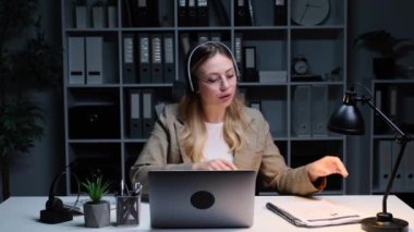 Evrak işleriyle uğraşan neşeli beyaz kadın çalışanlar. İnternet üzerinden görüşme ya da toplantı. Hepsi de akşam ofisinde dizüstü bilgisayarla çalışıyor..