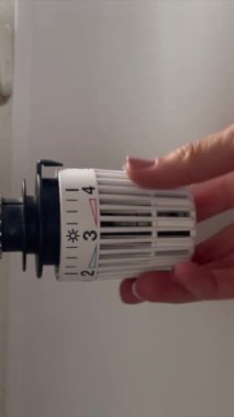 Beyaz bir kadının ev oturma odasındaki ısıtıcının sıcaklığını yakından çek. Uyumlu bir iklim ve verimli bir ısınma kavramı. Dikey video.