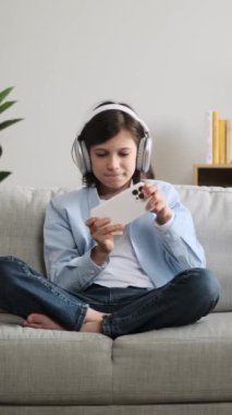 Video oyununda oynayan neşeli, beyaz bir çocuk. Telefonla oynuyor ve evde galibiyeti kutluyor. Çevrimiçi rekabet kavramı. Dikey video.