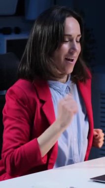 Oyuncu, beyaz kadın, orta yaşlı, serbest çalışan, gece geç saatlerde çalışırken müzik eşliğinde dans eden. Dikey video.