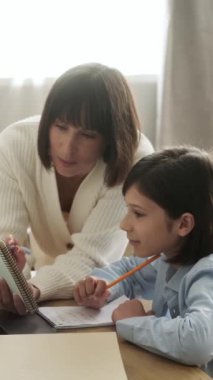 Mutlu beyaz anne ve okul çocuğu ev ödevi yapıyor, evde öğreniyor. E-öğrenim, öğrenim ve eğitim konsepti. Dikey video.