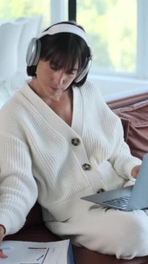 Düşünceli Kafkasyalı orta yaşlı iş kadını evde laptop ve belgelerle çalışıyor. Çevrimiçi çalışma kavramı. Dikey video.