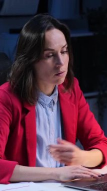 Kafkasyalı orta yaşlı kadın ofis çalışanı gece geç saatlerde bilgisayarla çalışırken facepalm jesti yapıyor. Dikey video.