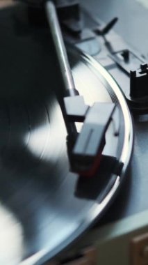 Klasik ses, müzik çalar ve kadın iğneyi yerleştirirken dönen vinil plağın yakın plan çekimi. Retro ses döner tablosu. Dikey video.
