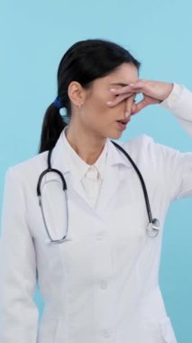 Sinirli ve rahatsız olmuş Kafkasyalı genç bir doktor ya da mavi arka planda iğrenç bir koku hisseden bir hemşire. Tatminsiz ve berbat bir koku. Dikey video.