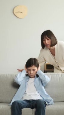 Öfkeli beyaz orta yaşlı anne evde bağırıyor ve üzgün bir çocuk yetiştiriyor. Ebeveynlik sorunları kavramı. Dikey video.